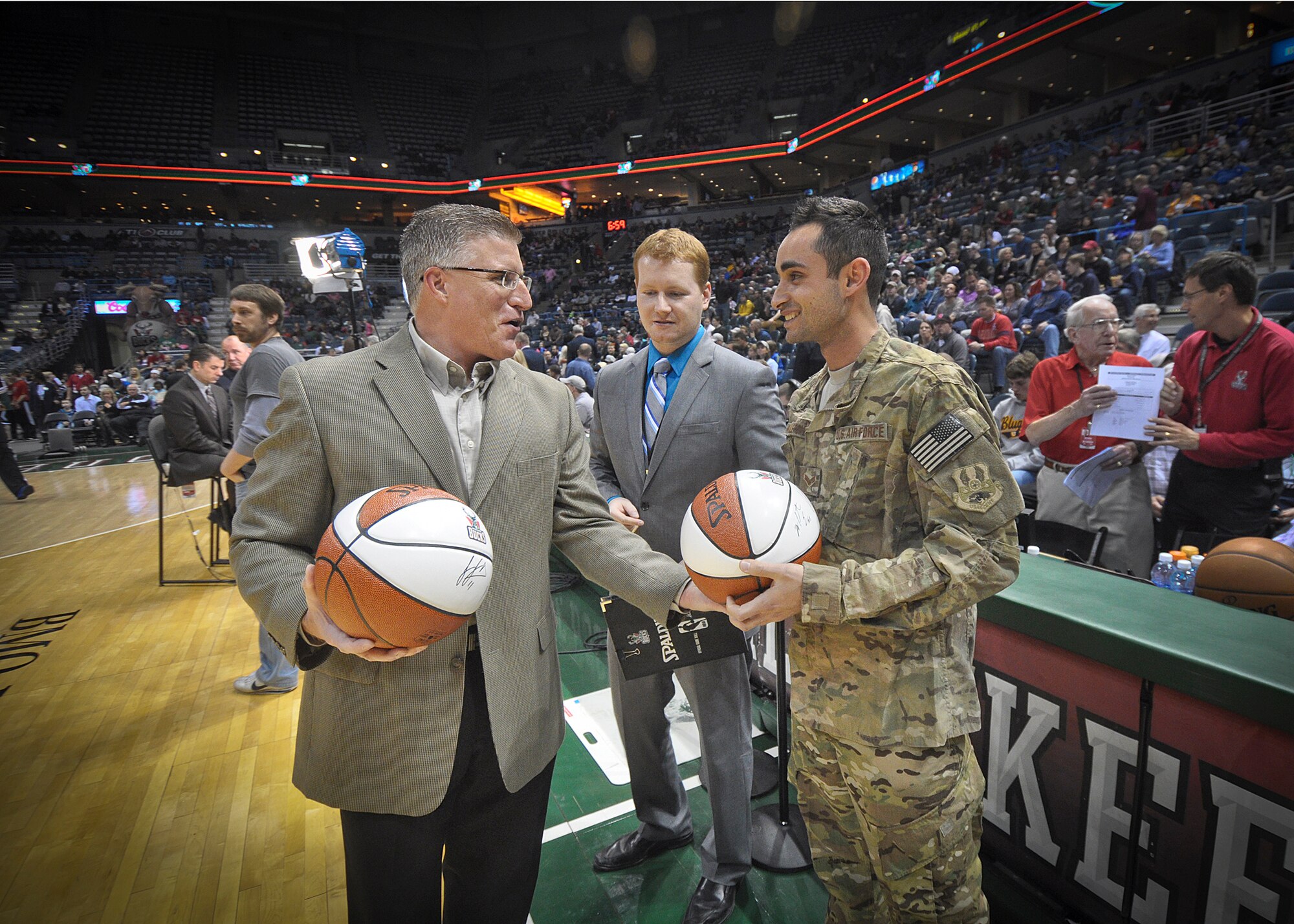 Michael Steger of Waukesha Metal hands an autographed souvenir basketball to Senior Airman Jefferson Harkleroad following a recognition ceremony at center court of the BMO Harris Bradley Center in Milwaukee, Wed., April 3, 2013.
Harkleroad, an electrician serving in the Civil Engineering Squadron of Milwaukee's 128th Air Refueling Wing, recently returned from a deployment to Afghanistan and was recognized prior to the Bucks game against the Minnesota Timberwolves as part of the “Hardwood Homecoming” program. (Air National Guard Photo by 1st Lt. Nathan Wallin / Released)