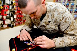 U.S. Marine Corps Cpl. Landon Beaty, Air Force Mortuary Affairs Operations, measures the space between a shooting badge and the ribbons of a uniform being prepared for a fallen Marine April 2, 2013, on Dover Air Force Base, Del. Marine Corps liaisons spend up to three hours perfecting one uniform, removing loose threads, aligning the anchor buttons and ensuring decorations are in the proper order. (U.S. Air Force photo/David Tucker)