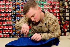 U.S. Marine Corps Staff Sgt. John Clements, Air Force Mortuary Affairs Operations, removes loose threads from a pair of Marine Corps dress blues trousers April 2, 2013, on Dover Air Force Base, Del. The pants are part of the uniform for a fallen Marine who was being sent home. (U.S. Air Force photo/David Tucker)