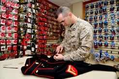 U.S. Marine Corps Cpl. Landon Beaty, Air Force Mortuary Affairs Operations, removes loose threads from a uniform April 2, 2013, on Dover Air Force Base, Del. Beaty assembled the uniform for a fallen Marine who was being sent home. (U.S. Air Force photo/David Tucker)