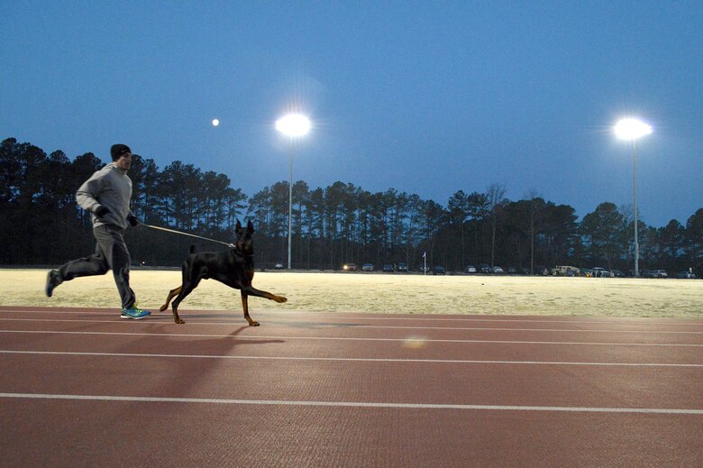 Senior Airman Tom Meehan, a TACP assigned to the 14th Air Support Operations Squadron, runs laps with his dog, Ruger, at the Hedrick Stadium track during the second annual worldwide TACP 24-hour Challenge Run, March 28-29.  The event is held to honor and raise funds for fallen TACP brothers in arms and their families.  (U.S. Air Force photo by Marvin Krause/Released)  