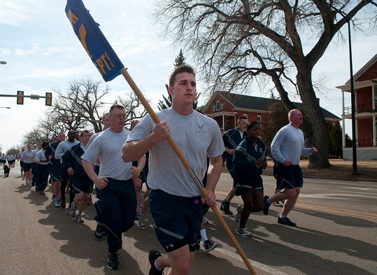 Senior Airman Craig Eveland, 90th Security Support Squadron, carries his squadron’s guidon as he leads them down Randall Avenue on F. E. Warren Air Force Base March 29. Eveland and his fellow Airmen were taking part in the 90th Security Forces Group two-mile “pride run.” (U.S. Air Force photo by R.J. Oriez)