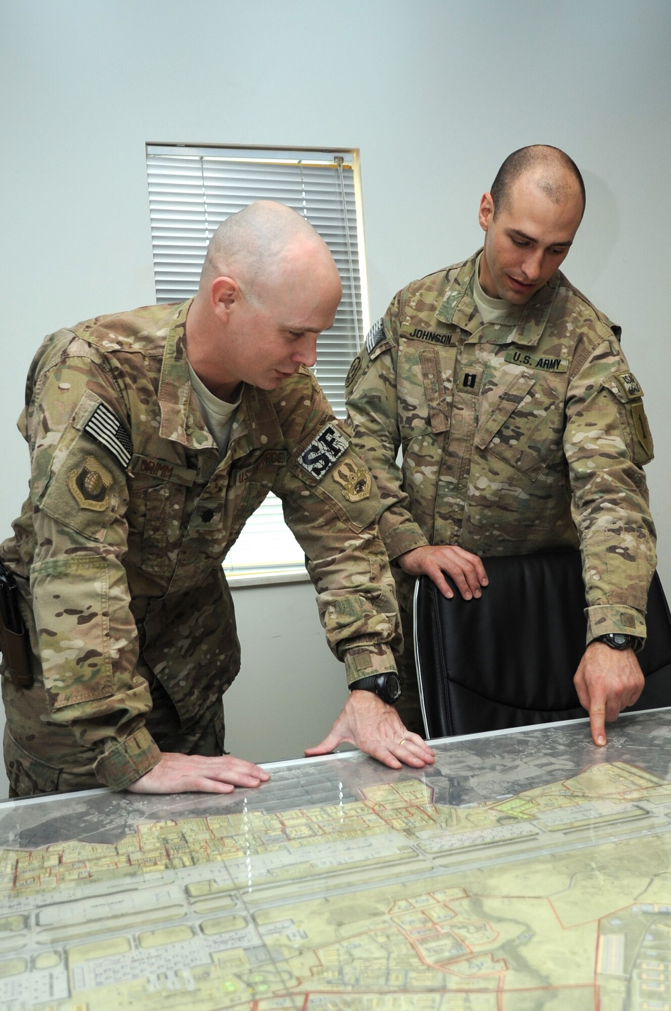 Lt. Col. John Grimm, 455th Expeditionary Security Forces Group deputy commander, and U.S. Army Capt. Ryan Johnson, Task Force 455 assistant operations officer, discuss plans in the 455th ESFG conference room March 12, 2013. The 455th ESFG, also known as Task Force 455 under Regional Command-East, is responsible for a 200-mile Base Security Zone and the protection of more than 42,000 personnel. (U.S. Air Force photo/Staff Sgt. David Dobrydney)