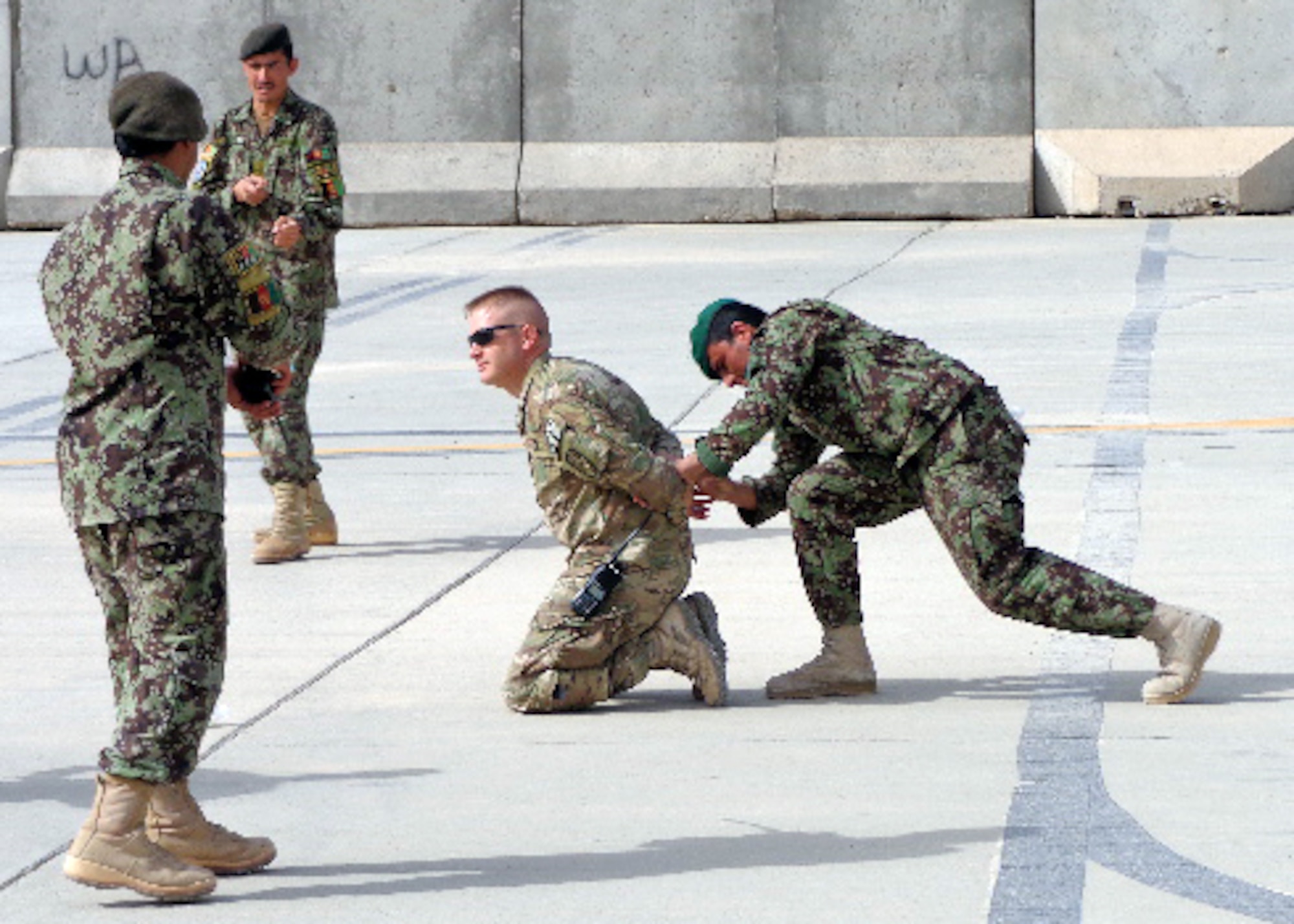 Members of Kandahar Air Wing security forces practice handcuffing Master Sgt. Chad Roberts, 738th Air Expeditionary Advisory Group security forces advisor, during a class at Kandahar Airfield, Afghanistan. AAF members with KAW security forces underwent training in order to assume flightline security responsibilities. Advisors with NATO Air Training Command-Afghanistan developed and lead the six-day training course for 15 AAF security forces members to include both classroom and hands-on instruction. (courtesy photo)