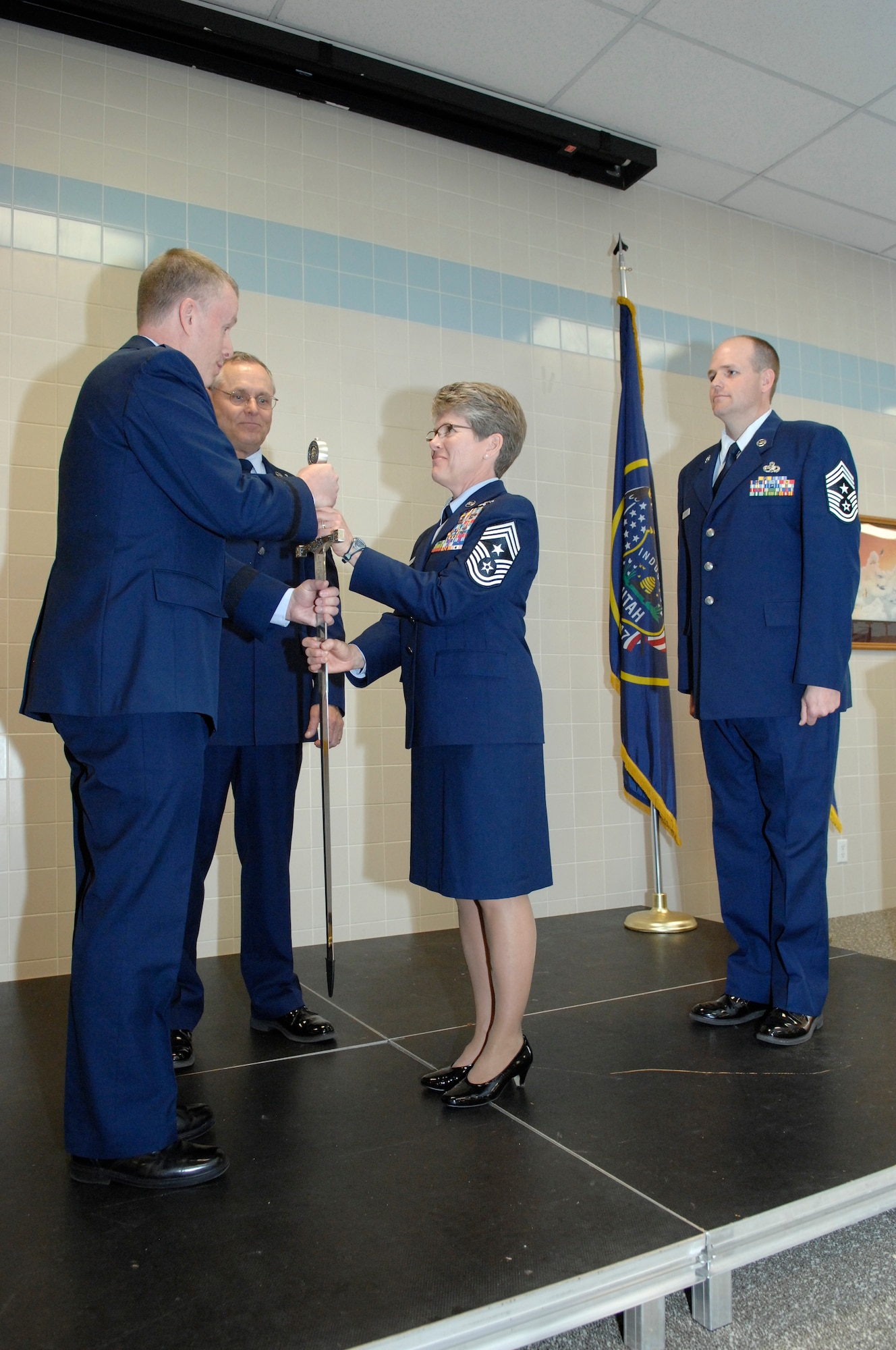 Relinquishing her position as the top enlisted service member in the Utah Air National Guard, State Command Chief Master Sgt. Denise Rager passes the sword to the Director of the Utah National Guard's Joint Staff, Brig. Gen. Kenneth L. Gammon, during a ceremony at the Utah ANG base, April 6. In the passing-of-the-sword ceremony, the sword represents the duties and responsibilities of the State Command Chief Position. Chief Master Sgt. Michael Edwards then assumed position as the new State Command Chief. (U.S. Air Force photo by Senior Master Sgt. Gary Rihn)(RELEASED)