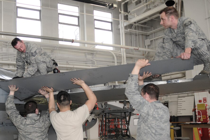 Tech. Sgt. Orval Head (top left), Tech. Sgt. Justin Wiebbecke (top right), Airman 1st Class Brock Logan (bottom left), Senior Airman Anthony Cam (bottom middle), and Staff Sgt. Travis Wagner (bottom right) work to attach a right hand flaperon to an F-16 aircraft, tail number 265, in the hangar of the 132nd Fighter Wing (132FW), Des Moines, Iowa on April 7, 2013.  This is the last 300 hour phase inspection for the 132FW, as the unit will be taking on a new mission working with MQ-9 Reaper remote piloted aircraft in the near future.  (Air National Guard photo/Staff Sgt. Linda K. Burger)(Released)