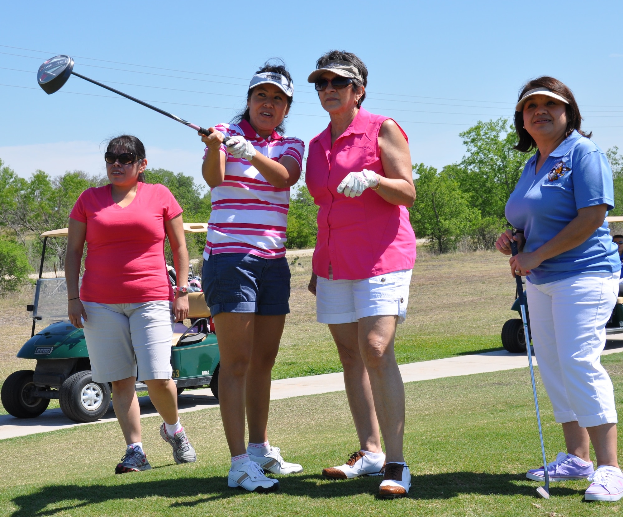 Tech Sgt. Valerie Rodriguez, 433rd Aerospace Medicine Squadron, left, and Chief Master Sgt. Maria Reyes, 433rd Medical Group, right, look on as Senior Master Sgt. Anita Garcia, 433rd AMDS, center, gives golfing tips to retired Chief Master Sgt. Jo Anne Henderson at the Inaugural MXG Golf Tournament held April 5 at the Alsatian Golf Club in Castroville, Texas.  The team was the only ladies team in the event. (U.S. Air Force Photo by Tech Sgt. Carlos Trevino)