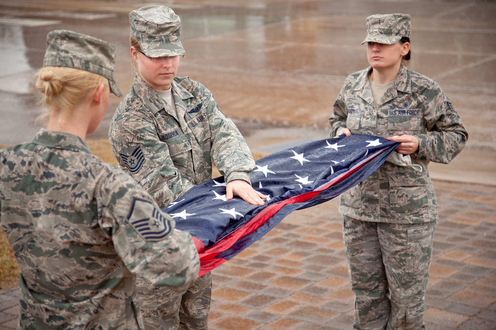 Master Sgt. Rachel Lohmann, Tech. Sgt. Lindsay Rosenow, and Staff Sgt. Sara Wendt fold the American flag during the retreat ceremony Saturday.  Airmen from the 934th Aeromedical Evacuation Squadron performed the flag ceremonies throughout the April Unit Training Assembly weekend at the Minneapolis-St. Paul Air Reserve Station, Minn. (U.S. Air Force photo/Shannon McKay)