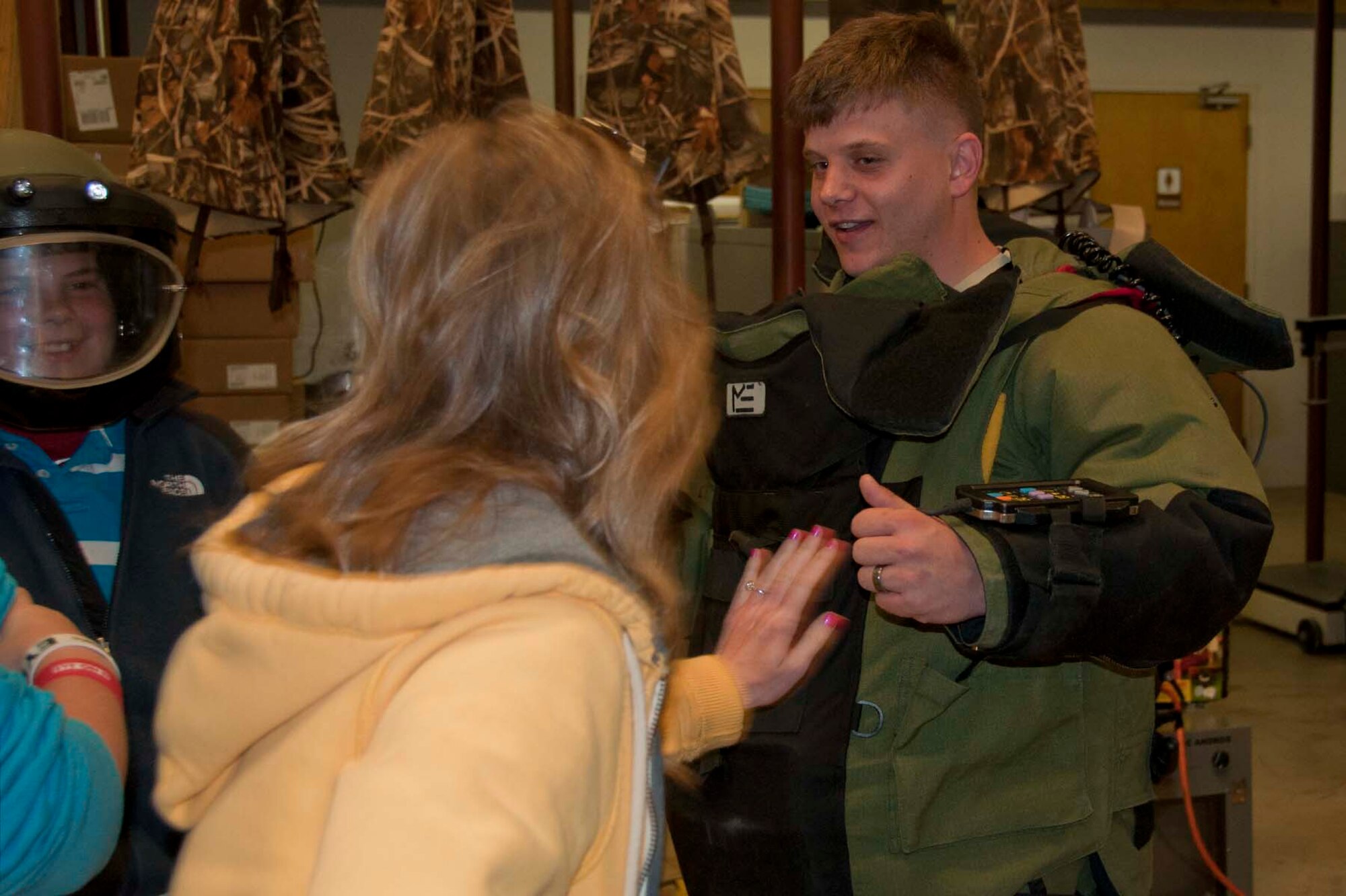 A chaperone from Trinity Christian School in Texarkana, Ark., taps on the protective suit of U.S. Air Force Airman 1st Class, Tim Habedank, a 2nd Civil Engineering Squadron explosive ordinance disposal technician at Barksdale Air Force Base, La., April 5, 2013.  Habedank allowed students and chaperones alike to push and tap against a hard plate in the suit to better understand how it protects EOD members when they are working with live explosives.  He explained EOD members normally approach explosives with a remote-controlled robot. The school children and their chaperones were able to view the robot and the rest of the building while visiting with members of the EOD team and learning about various aspects of their job in the U.S. Air Force.   (U.S. Air Force photo by Tech. Sgt. Ted Daigle/Released) 