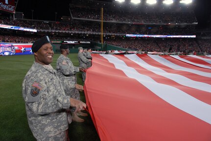 Maj. Bernard Napier, with the D.C. National Guard's 74th Troop Command, holds one of two giant American flags unfurled on the outfield during pre-game ceremonies for the Inaugural Game at Nationals Park in Washington, D.C., on March 30, 2008. The D.C. Air National Guard's 121st Fighter Squadron also provided an F-16 Fighting Falcon flyover.