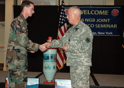 New York Air National Guard Staff Sgt. Thomas McCauley, left, from the 109th Airlift Wing, presented Command Sgt. Maj. David Ray Hudson with a jet-assisted takeoff (JATO) bottle during the National Guard Bureau's first Senior Enlisted Leaders Conference in mid-April. Hudson, the Guard Bureau's senior enlisted leader, led the four-day conference for Army and Air Guard enlisted leaders in Saratoga Springs, N.Y. The Air Guard uses JATO bottles to give aircraft such as C-130 transports extra thrust during difficult takeoff situations.