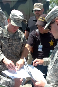 Arkansas Army National Guard Staff Sgt. Lucas Jennings discusses tornado response missions May 12 with other Citizen-Soldiers and local law enforcement representatives in a central Arkansas area affected by a May 10 tornado.