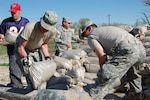 Soldiers from the Wyoming Army National Guard's 133rd Engineer Company, and a local civilian, prepare sand bags to be stacked along the banks of the Little Snake River in Baggs, Wyo., May 21, 2008, to prevent the town from flooding. The 33 Soldiers work in 12 hour shifts. The unit has been working to save the town since May 19.