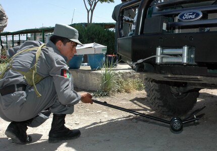 An Afghan National Police officer checks a vehicle's undercarriage during a vehicle-search class at the Parwan province's police headquarters in the Charikar district, June 3, 2008. The class is given as part of ongoing training the ANP receive from a team of Idaho National Guardsmen.