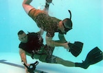 Experienced salvage diver Sgt. Lance Little (top) "attacks" Sgt. Roel Ramos during repeated pool "hits" by taking off his mask and removing his swimming fins. Prospective dive school students must overcome panic and perform corrective actions with one precious breath of air.