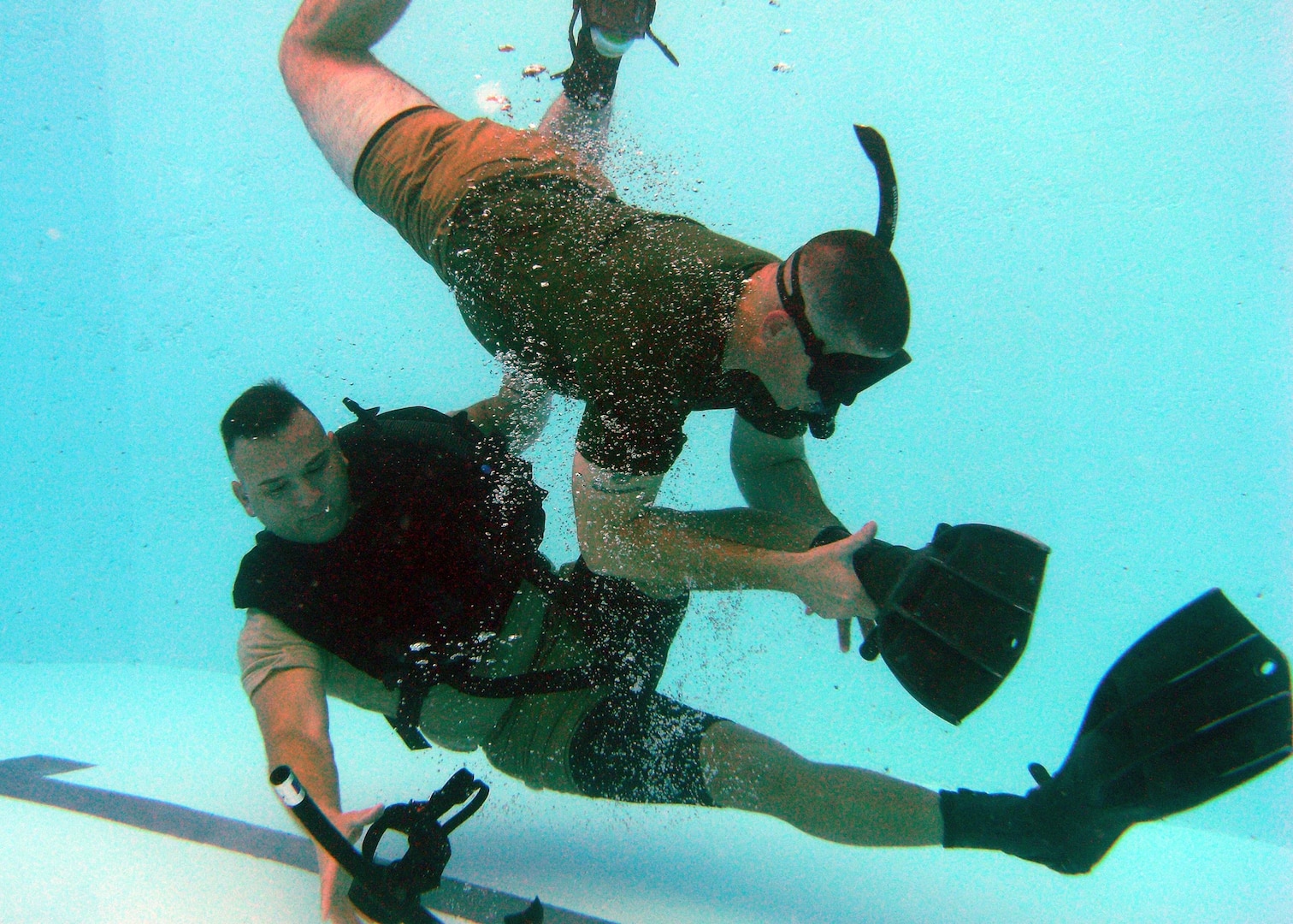 Experienced salvage diver Sgt. Lance Little (top) "attacks" Sgt. Roel Ramos during repeated pool "hits" by taking off his mask and removing his swimming fins. Prospective dive school students must overcome panic and perform corrective actions with one precious breath of air.