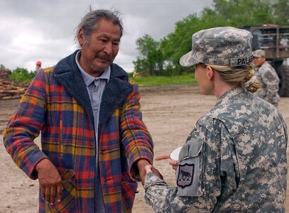 Pine Ridge Reservation resident Oren Shoulders shakes hands with Sgt. 1st Class Kristie Palmer of the 109th Regional Support Group, South Dakota Army National Guard, during a timber-haul mission on June 5 to the Pine Ridge Reservation in Manderson, S.D.