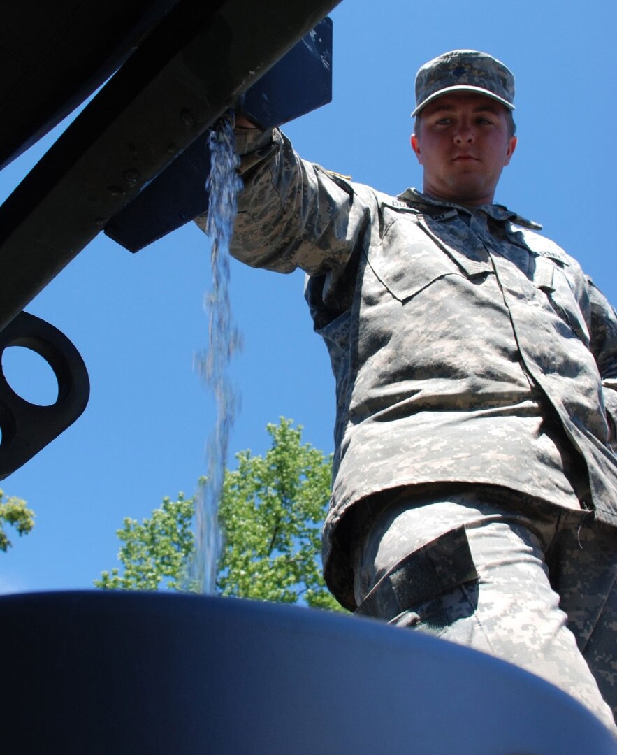 Indiana Army National Guard Spc. Daniel Dubowski dispenses water into a container for a Hope, Ind. resident, Wednesday, June 11, 2008. Dubowski, a mechanic with the 113th Engineer Battalion headquarted in Gary, Ind., deployed to southern Indiana as part of Operation Noah's Ark.