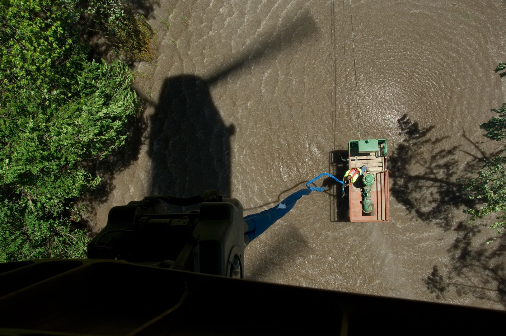 An employee from the Cedar Rapids Water Utility prepares to attach a lift cable from an Iowa Army National Guard CH-47 Chinook to a damaged water pump on the Iowa River near Cedar Rapids, Iowa. The CH-47 from Bravo Company, 2-11 General Aviation Support Battalion was used recover several water pumps in need of repair following massive flooding caused by heavy rains in Iowa. The pumps will be repaired and put back in place to provide fresh water for the residents of Cedar Rapids.