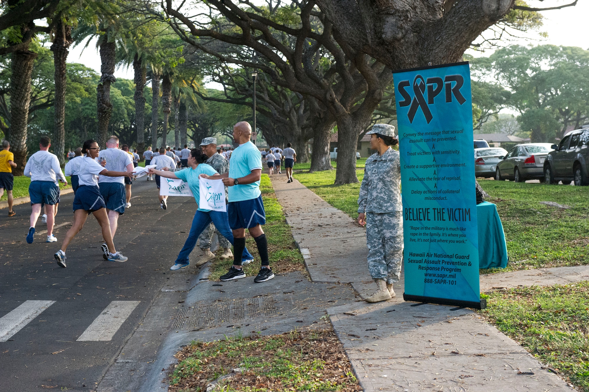 Sexual Assault Prevention and Response Program victim advocates pass out towels during the 15th Wing fun run at Joint Base Pearl Harbor-Hickam, Hawaii, April 5, 2013. In honor of Sexual Assault Awareness Month, the victim advocates assembled to educate the base community on the importance of the SAPR program by passing out literature and other promotional items while cheering on their fellow service members in the monthly run. Each April, the Department of Defense observes Sexual Assault Awareness and Prevention month and commits to raising awareness and promoting the prevention of sexual violence. This year's theme, "We own it... We'll solve it... Together," emphasizes the commitment to solving the problem of sexual assault. (U.S. Air Force photo/Staff Sgt. Terri Paden)