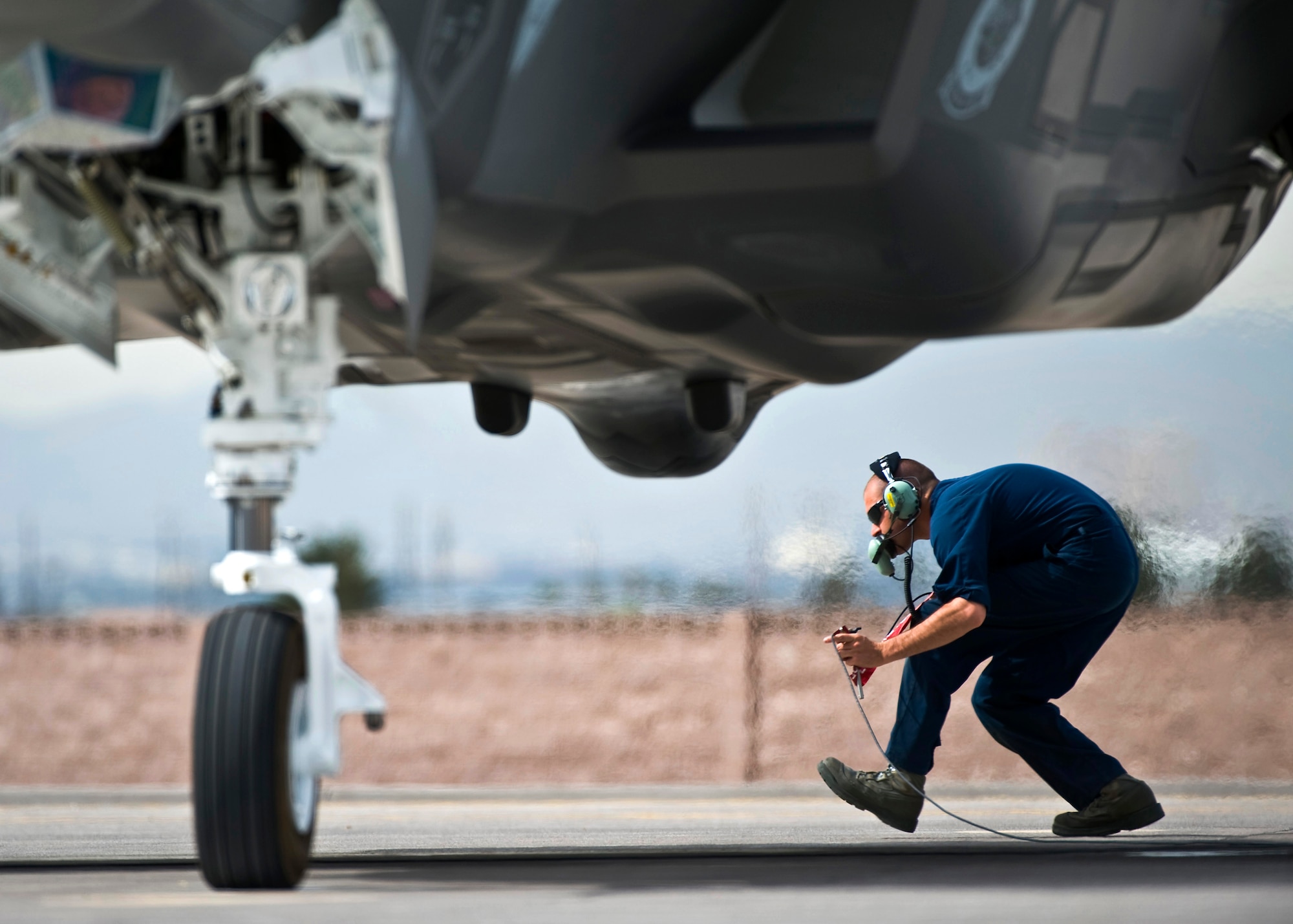 U.S. Air Force Senior Airman Alexander Orchard, 57th Aircraft Maintenance Squadron crew chief, crouches underneath the exhaust of an F-35A Lightning II before a training mission April 4, 2013, at Nellis Air Force Base, Nev. The F-35A is assigned to the 422nd Test and Evaluation Squadron and maintained by the 57th AMXS Lightning Aircraft Maintenance Unit. (U.S. Air Force photo/Senior Airman Brett Clashman)