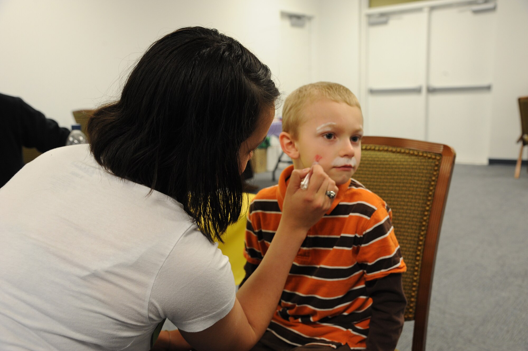 Landon, son of Senior Airman James Dreitzler, 741st Missile Security Forces Squadron member, sits patiently as volunteer 2nd Lt. Kimberly Erskine, 12th Missile Squadron ICBM deputy combat crew commander, paints a tiger on his face at the Youth Center on March 30. Children of all ages played games, had their photo taken with the Easter bunny and won prizes. (U.S Air Force photo/Airman 1st Class Katrina Heikkinen) 