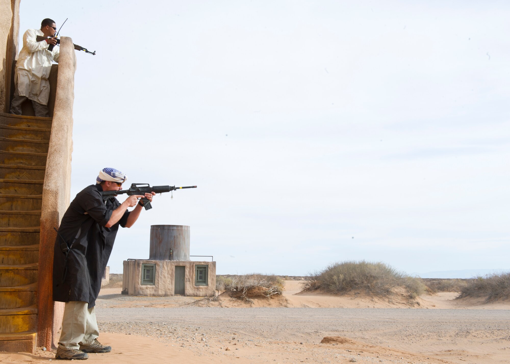 Two Rally Point Management contractors act as opposing forces during a simulated ground engagement as part of a Remotely Piloted Aircraft training scenario at White Sands Missile Range, N.M., April 5. Col. Andrew Croft, 49th Wing commander, and 49th Wing Command Chief Master Sgt. James Patrie were invited to participate in the Rally Point Management scenarios as the opposing force during an RPA training flight with students from Holloman Air Force Base, N.M. Rally Point Management trainers are experts on Joint Terminal Attack Controller (JTAC) and Close Air Support (CAS) procedures as well as ground warfighter equipment and software applications. The opportunity to be a part of the ground training scenarios helped 49th Wing leadership better understand RPA aircrews training experience here at Holloman AFB. (U.S. Air Force photo by Senior Airman DeAndre Curtiss/Released) 