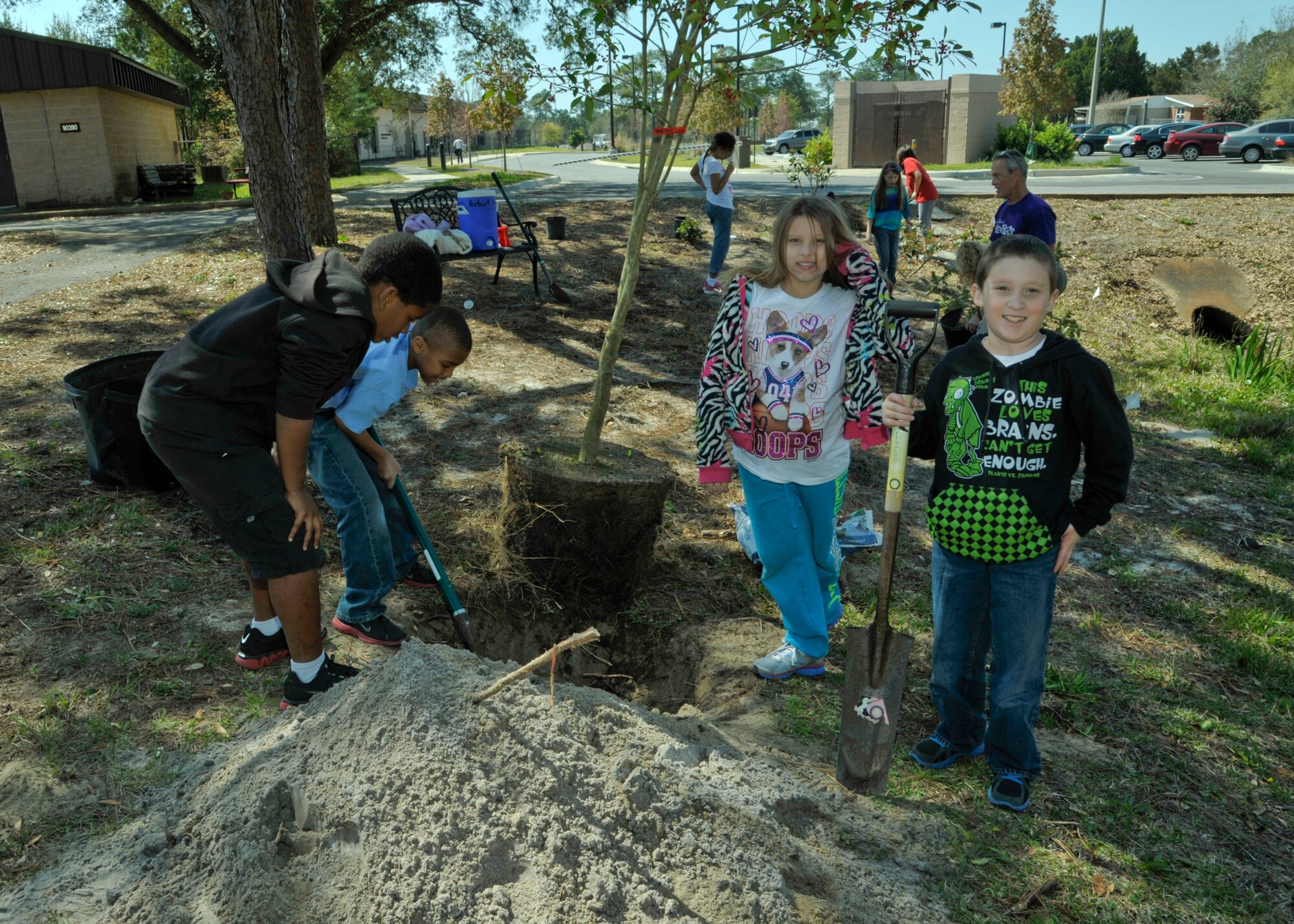Children smile and work as they plant trees and shrubbery near the Artisan Well on Hurlburt Field, Fla., March 29. "Planting trees is important and I got to help plant them," said Darren D'alessandro, son of Tech. Sgt. April D'alessandro - non-commissioned officer in charge of intelligence at the 10th Combat Weather Squadron and Master Sgt. Dana D'alessandro - intelligence analyst of the 11th Intelligence Squadron. "Trees give us oxygen so we can live." (U.S. Air Force photo/ Airman 1st Class Nigel Sandridge)