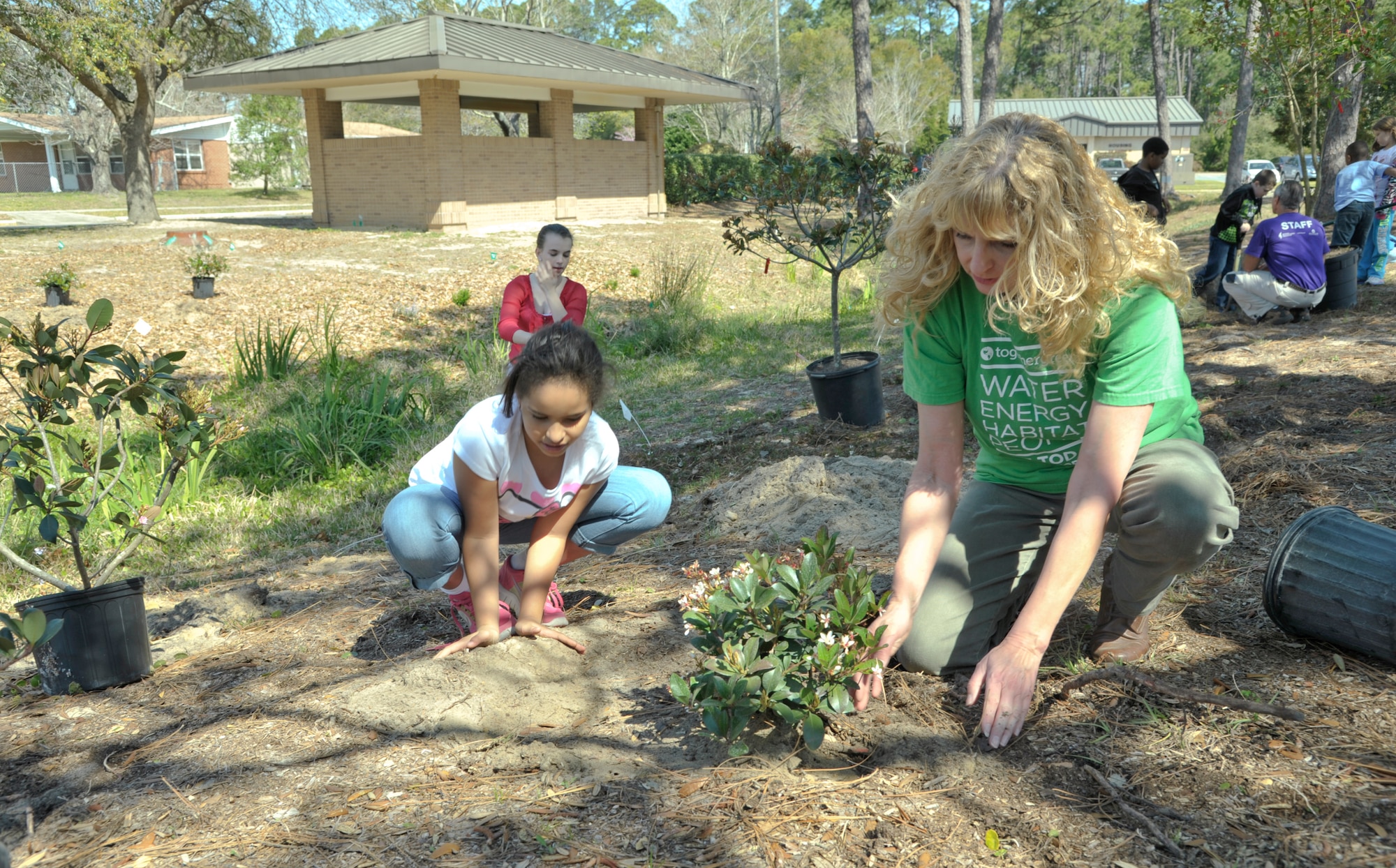 Bailey Shine, daughter of Jeffery Shine – a contractor for the Special Operations Forces Planning, Rehearsal and Execution Preparation, and Vivienne Wright-Shine, assists Catherine Goss, operations clerk of the Hurlburt Child Development Center and nature program advocate for the Air Force, in planting new tree sprouts near the Artisan Well on Hurlburt Field, Fla., March 29.  Children participated in an outdoor environmental exercise that educated them on the benefits of wild plant life. (U.S. Air Force photo/ Airman 1st Class Nigel Sandridge)