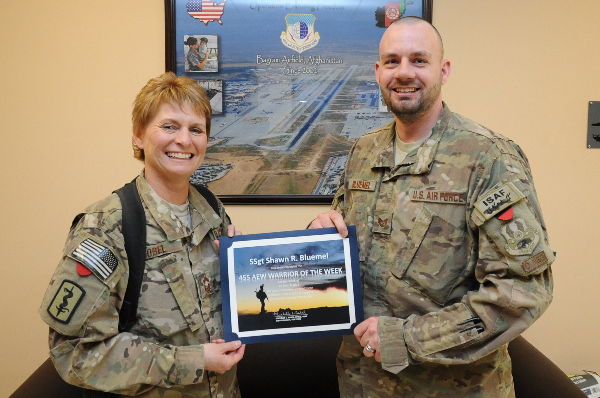 Chief Master Sgt. Michelle Sobel, 455th Expeditionary Medical Group superintendent, presents the "Warrior of the Week" award to Staff Sgt. Shawn Bluemel, 455th Air Expeditionary Wing command post systems NCO in charge, on Bagram Airfield, Afghanistan, April 3, 2013. Bluemel ensures day-to-day communications for the command post are maintained and operational. (U.S. Air Force photo/Staff Sgt. David Dobrydney)