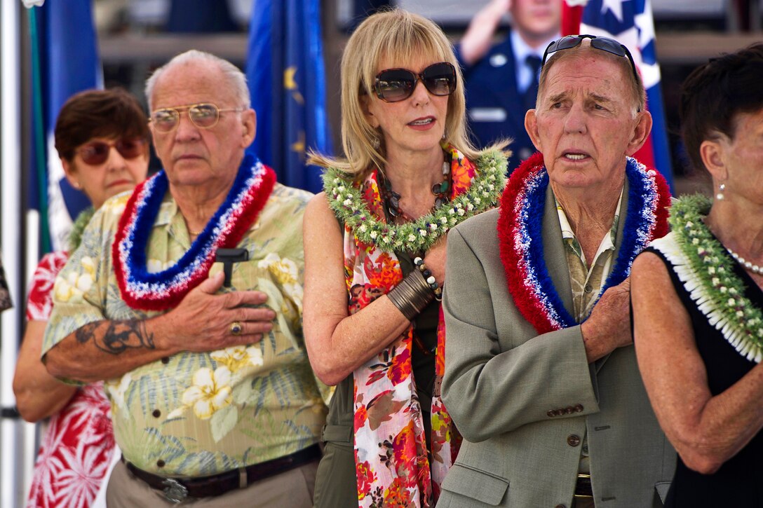 Retired Marine Corps Chief Warrant Officer 4 William Thomas, left, and retired Navy Capt. Jerry Coffee, second from right, former prisoners of war, show respect during the singing of the national anthem at the commemorative ceremony marking the 40th anniversary of Operation Homecoming on Joint Base Pearl Harbor-Hickam, Hawaii, April 4, 2013. In 1973, the last prisoner of war from Vietnam landed on what was then Hickam Air Force Base.
