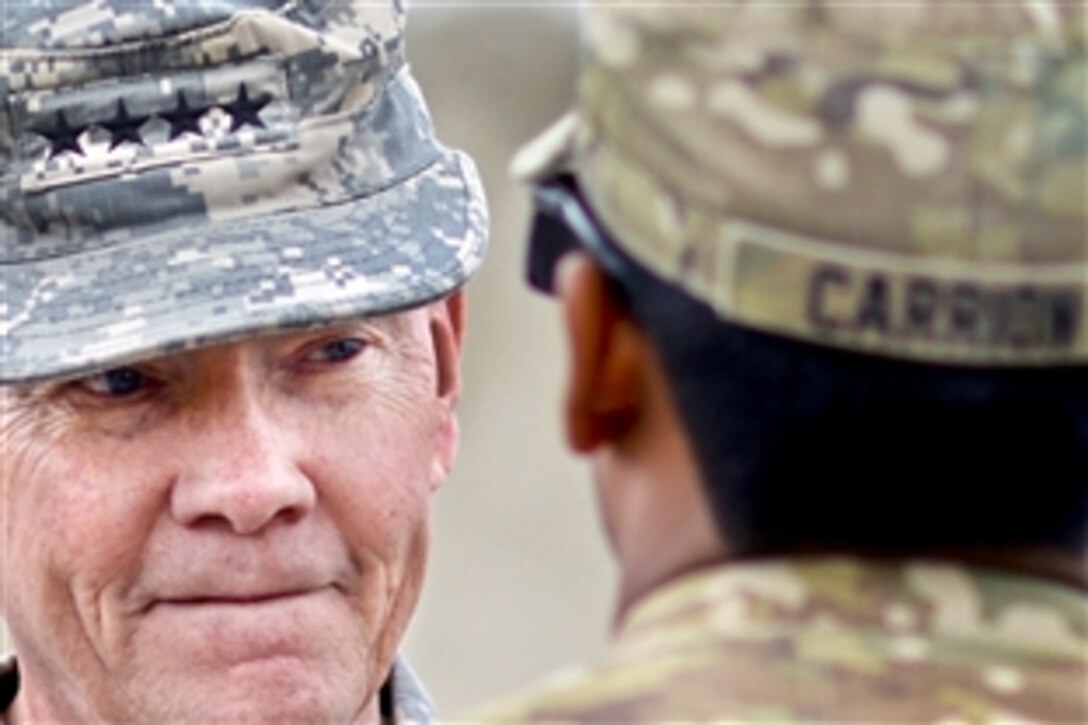 U.S. Army Gen. Martin E. Dempsey, left, chairman of the Joint Chiefs of Staff, talks with a service member after presenting an award to him on Forward Operating Base Sharana in Paktika province, Afghanistan, April 7, 2013.