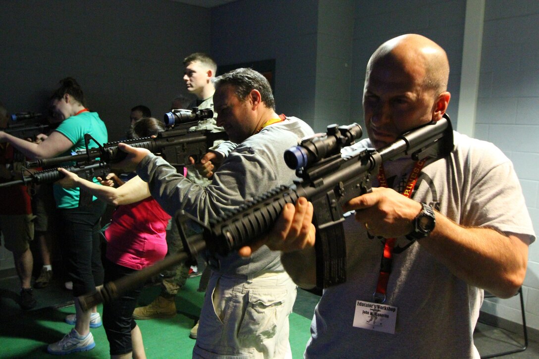 Right, John Acquavita, a teacher from Wilber Cross High School in New Haven, Conn., shoots a simulated M16-A4 rifle in the Indoor Marksmanship Simulated Marksmanship Trainer alongside other educators from Vermont, Rhode Island, Connecticut and Massachusetts, during the Educators Workshop on Marine Corps Recruit Depot Parris Island, S.C., April 3, 2013. The workshop brings together teachers, administrators and other education professionals aboard the depot and gives them the opportunity to experience what recruit training is like in the Corps. (U.S. Marine Corps photo by Sgt. Richard Blumenstein)