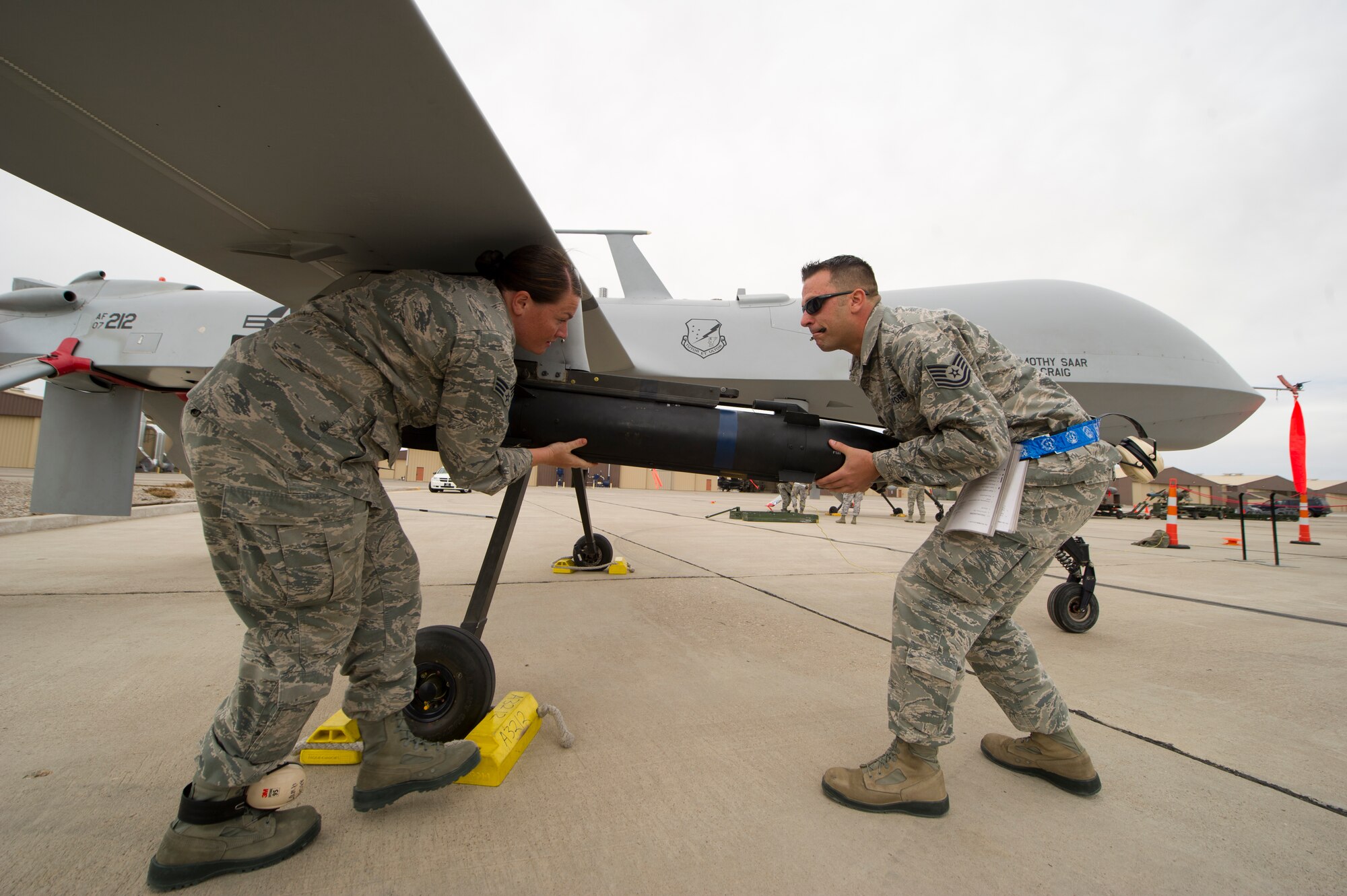 Senior Airman Bethany Lamb and Tech. Sgt. Travis Wheeler, 849th Aircraft Maintenance Squadron load team members, load an inert missile onto a MQ-1 Predator aircraft during the load-crew competition at Holloman Air Force Base, N.M., April 5. Load-crew competitions are held on a quarterly basis and are used to help build morale through friendly competition. (U.S. Air Force photo by Airman 1st Class Michael Shoemaker/Released)