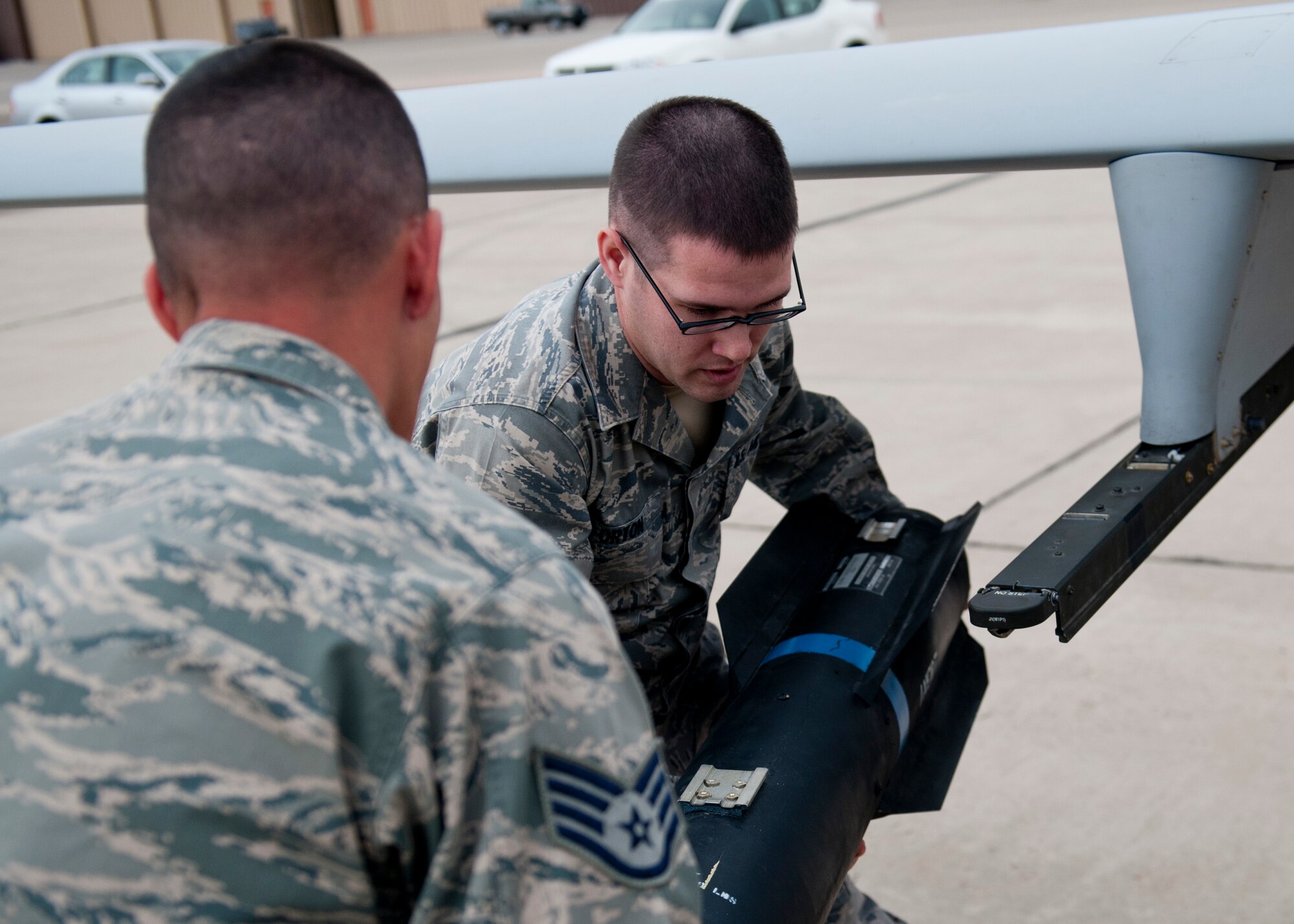 Staff Sgt. Michal Game and Senior Airman Randall Orton, both 849th Aircraft Maintenance Squadron, remove an inert missile from an MQ-1 Predator aircraft during a quarterly load-crew competition at Holloman Air Force Base, N.M., April 5. The 849th AMXS pitted two MQ-1 load-crews against each other for the first time to evaluate who could prepare the aircraft for combat the quickest and with the fewest procedural errors. (U.S. Air Force photo by Airman 1st Class Daniel E. Liddicoet/Released)

