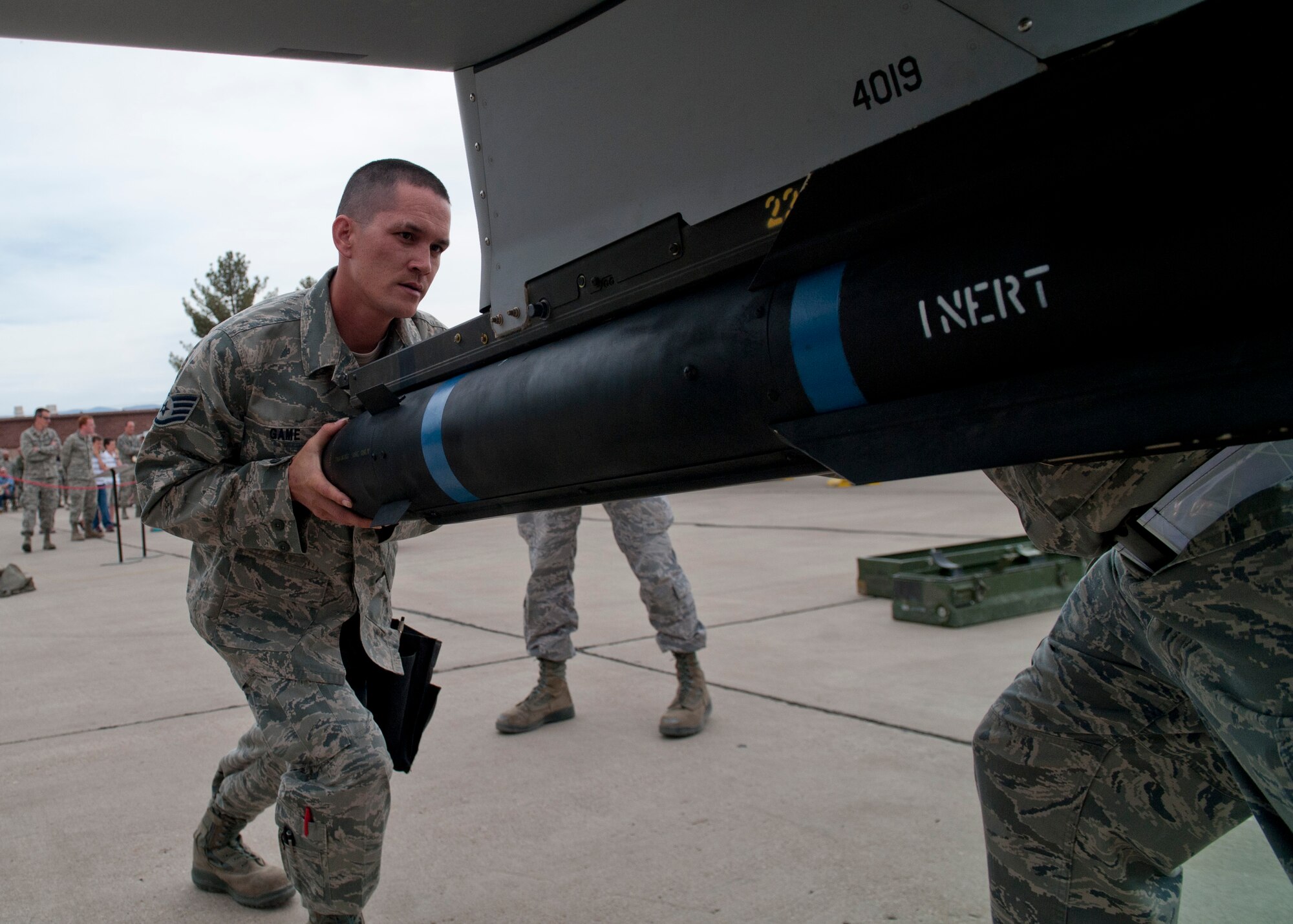 Staff Sgt. Michal Game, 849th Aircraft Maintenance Squadron, loads an inert missile onto an MQ-1 Predator aircraft during a quarterly load-crew competition at Holloman Air Force Base, N.M., April 5. The 849th AMXS pitted two MQ-1 load-crews against each other for the first time to evaluate who could prepare the aircraft for combat the quickest and with the fewest procedural errors. (U.S. Air Force photo by Airman 1st Class Daniel E. Liddicoet/Released)