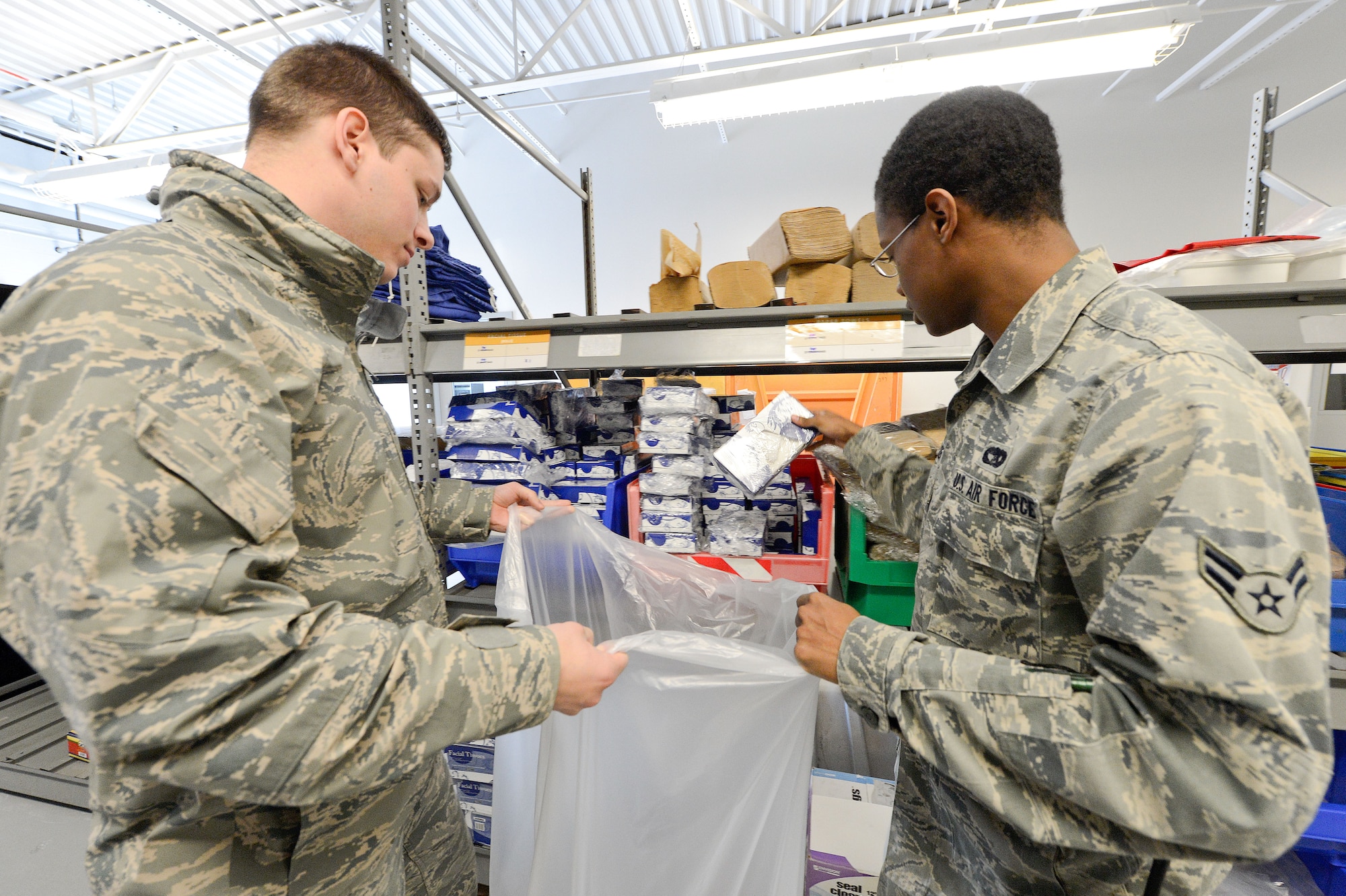 Senior Airman Noah Benefiel (left), 87th Aerial Port Squadron, Air Force Reserve Command and Airman 1st Class Brandon Walker, 436th Aerial Port Squadron, place consumable items in to a large bag to service an outgoing C-5M Super Galaxy flight from the 436th Airlift Wing, Dover Air Force Base, Del. The 436th Aerial Port Squadron, clean fleet services section, works out of the passenger terminal and is shown in-action March 28, 2013. (U.S. Air Force photo/Greg L. Davis)
