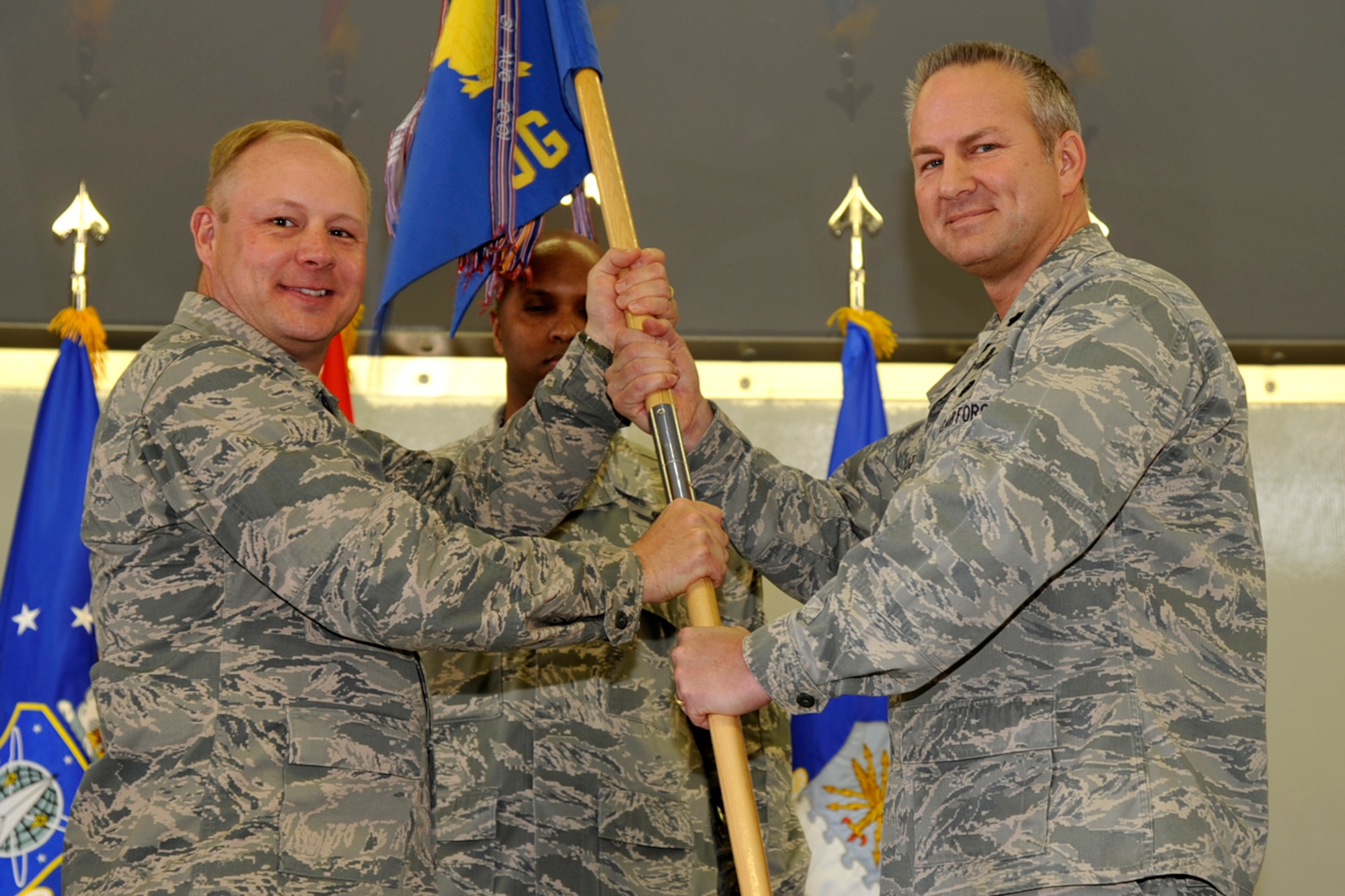 PETERSON AIR FORCE BASE, Colo. – Col. Chris Crawford (left), 21st Space Wing commander, passes the 21st Operations Group guidon to Lt. Col. Paul Tombarge, interim 21st OG commander, at a change of command March 29. Tombarge, who was recently selected for promotion to the rank of colonel, was the 21st OG deputy commander. The outgoing commander, Col. Jennifer Moore, will deploy to U.S. Air Forces Central Command in southeast Asia. (U.S. Air Force photo/Robb Lingley)
