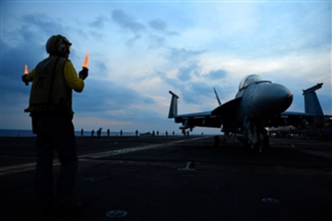 U.S. Navy Petty Officer 2nd Class Stuart Folmar uses lighted wands to direct the pilot of an F/A-18E Super Hornet on the flight deck of the aircraft carrier USS John C. Stennis (CVN 74) during flight operations on April 6, 2013.  The Stennis is deployed to the 7th Fleet area of responsibility to conduct maritime security operations and theater security cooperation efforts.  The Hornet is attached to Strike Fighter Squadron 41.  