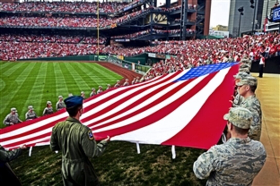 Airmen present a giant American flag for nearly 50,000 fans to see the Cincinnati Reds play the St. Louis Cardinals at Busch Stadium in St. Louis, Mo., April 8, 2013. The airmen are assigned to the 375th Air Mobility Wing, Scott Air Force Base, Ill. Service members from base have participated in numerous community sporting events, but this was the first time they presented the flag on the opening day.