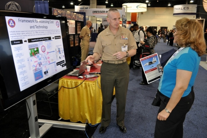 Lt. Col. William Yates, Modeling and Simulation program manager under Systems Engineering Interoperability, Architectures and Technology, discusses the Framework for Assessment of Cost and Technology with a visitor April 8 during the Sea-Air-Space Exposition at the Gaylord National Convention Center in National Harbor, Md. 