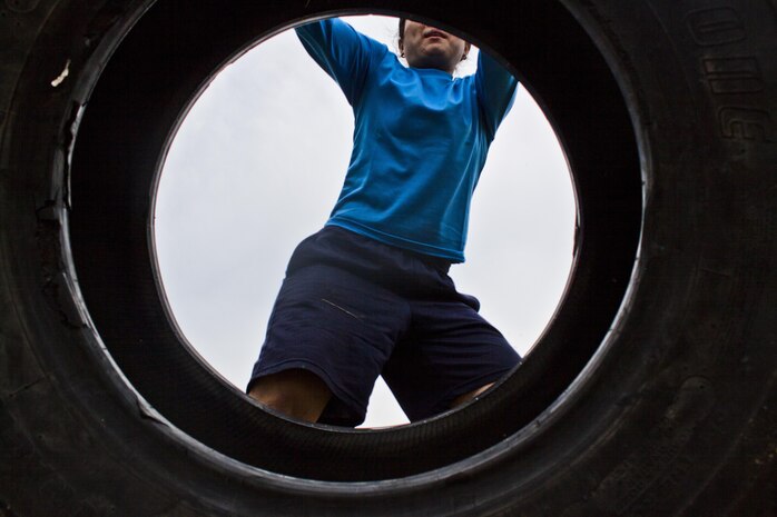 Sayaka Takabayashi, Marine Corps Community Services SemperFit fitness instructor, performs a tire flip exercise during Strongman pre-training, which took place behind the IronWorks Gym here April 4, 2013. The Strongman competition is planned to include a tire flip, Farmer’s Walk, Humvee pull and several other trials.
