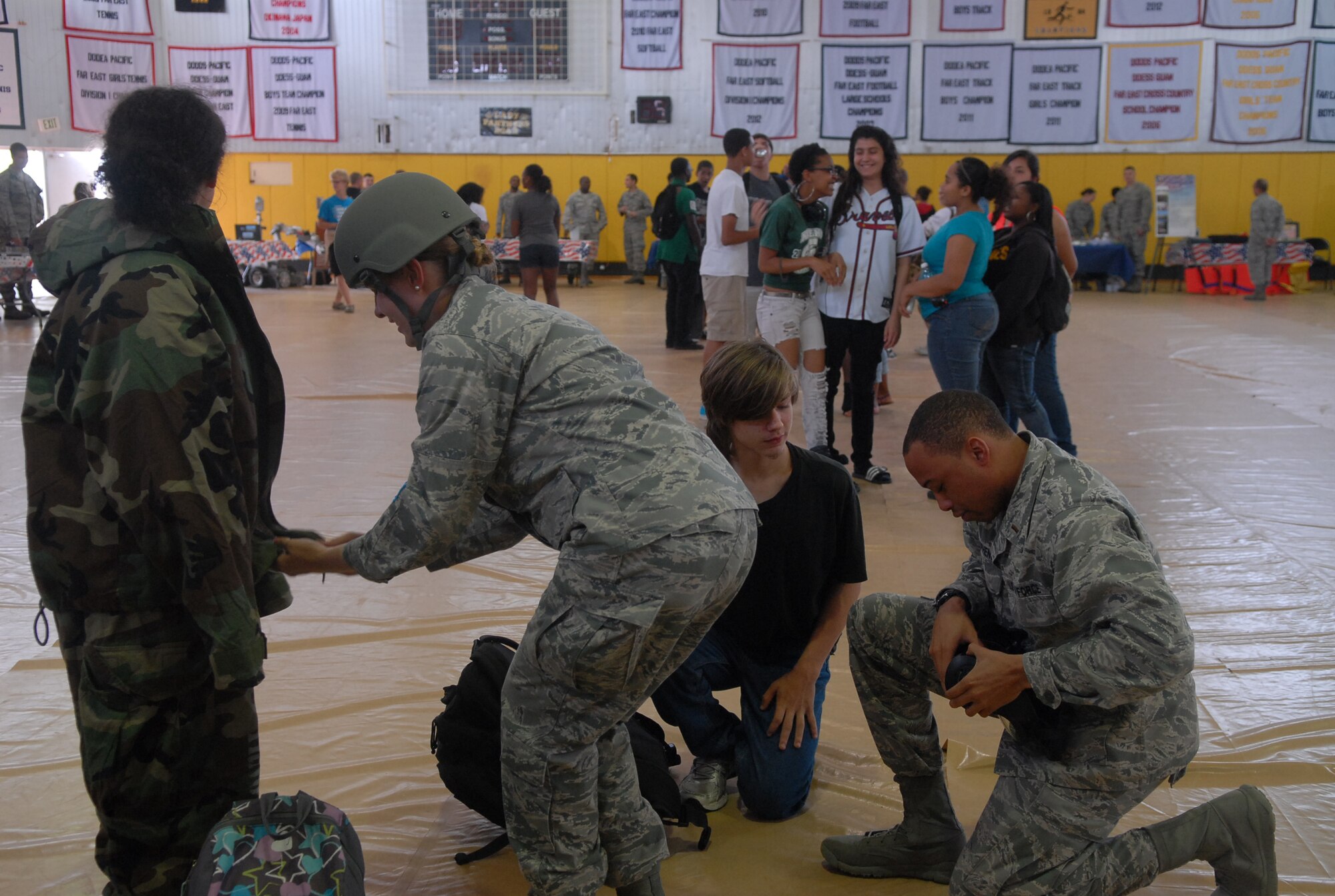 U.S. Air Force 2nd Lt. Paul Stephens and 1st Lt. Teresa Crampton, 18th Logistics Response Squadron, demonstrate protective gear with high school students during the Kadena High School Career Day on Kadena Air Base, Japan, April 4, 2013. Hosted by the Air Force Cadet Officer Mentor Action Program, the purpose of the event was to offer a glimpse of Airmen's daily duties to possible recruits. (U.S. Air Force photo by Staff Sgt. Lauren Snyder/Released)