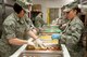 Senior Airman Sheryl Bustamante and Staff Sgt. Anya Davis of the 124th Fighter Wing Services Flight prepare lasagne that will be part of 