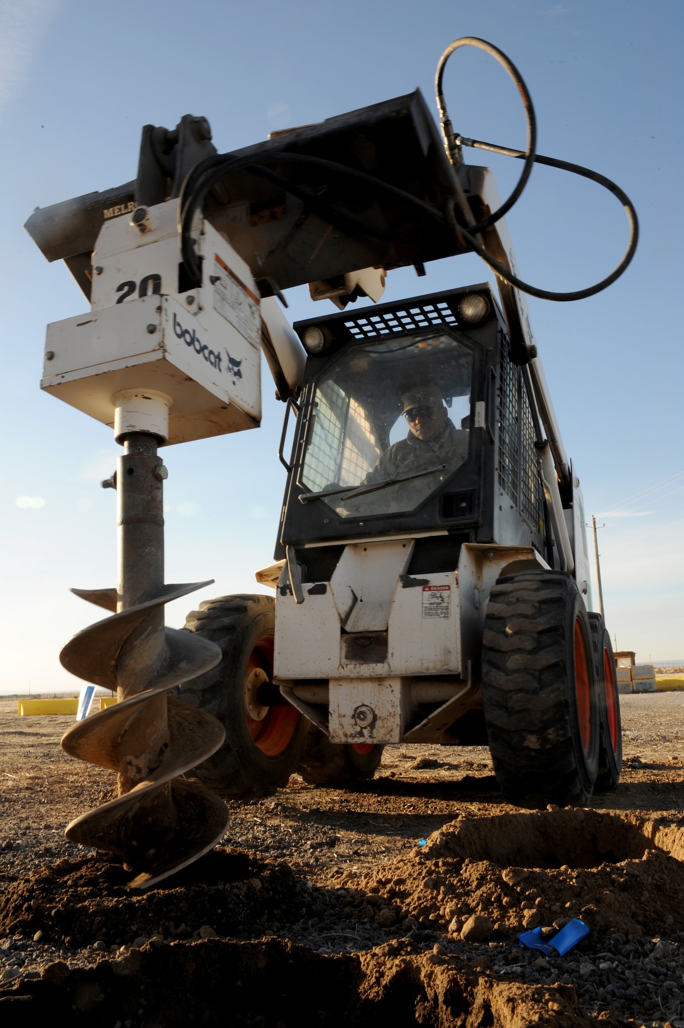 U.S. Air Force Senior Airman David Vaughner, 366th Civil Engineer Squadron pavement and equipment operator, drills holes with a skid steer in preparation for a revetment at a simulated deployed location, Mountain Home Air Force Base, Idaho, March 19, 2013. A revetment is a barrier that protects military assets and personnel from harm. (U.S. Air Force photo/Staff Sgt. Roy Lynch) (Released)