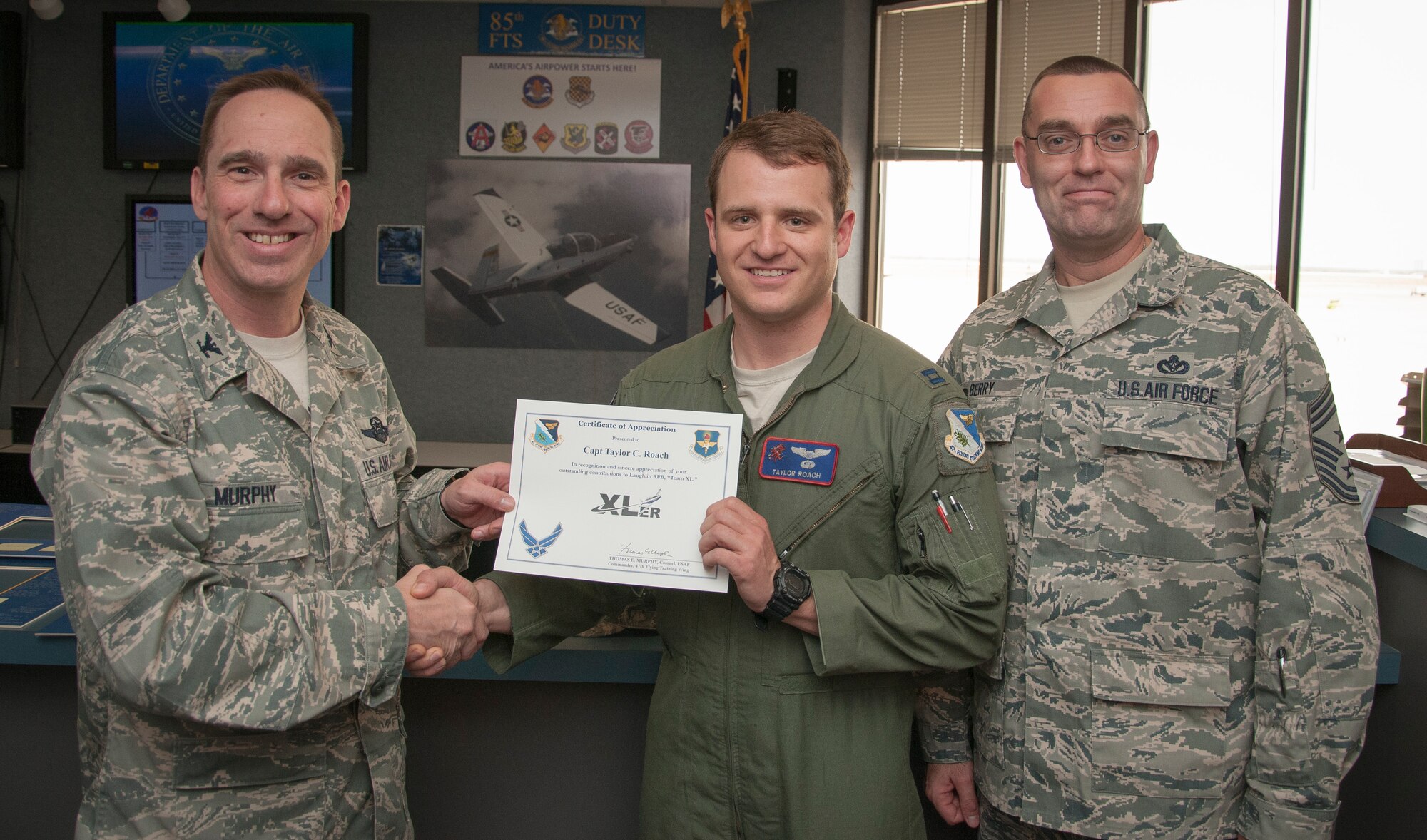 Capt. Taylor Roach, 434th Flying Training Squadron assistant flight commander, poses with Col. Tom Murphy, 47th Flying Training Wing commander, and Chief Master Sgt. Garry Berry, 47th FTW command chief, after being presented the XLer of the week award at Laughlin Air Force Base, Texas, March 20, 2013. The XLer is a weekly award chosen by wing leadership and given to those who consistently make outstanding contributions to Laughlin and their unit. (U.S. Air Force photo by Airman 1st Class John D. Partlow) 
