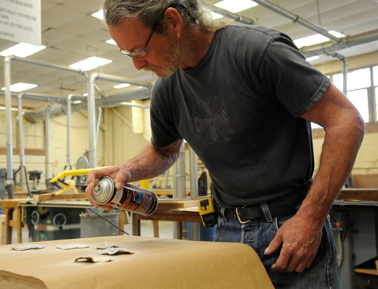 Mike Jarrett, 2nd Force Support Squadron woodcrafts center manager, sprays an adhesive on unit patches during the construction of a shadowbox on Barksdale Air Force Base, La., April 10, 2013. Jarrett builds retirement and going-away gifts, trophy cases, recognition boards, podiums and conference tables for Team Barksdale. (U.S. Air Force photo/Airman 1st Class Andrew Moua)