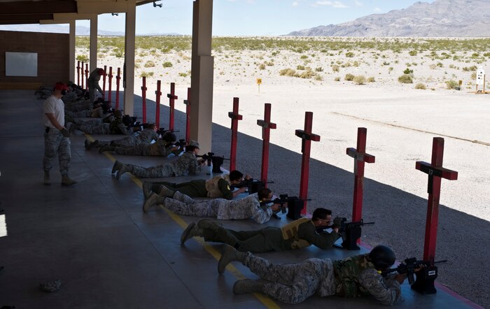 Nellis and Creech Air Force Base Airmen aim M4 carbine assault rifles down the firing range during a combat arms training and maintenance class April 9, 2013, at Nellis Air Force Base, Nev. Safety procedures on the range are key to ensure no one is injured during training. (U.S. Air Force photo by Senior Airman Matthew Lancaster)