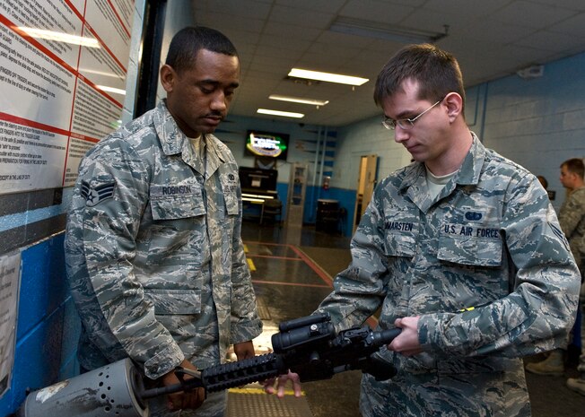 Senior Airman Kevin Robinson, 99th Security Forces Squadron combat arms instructor, watches Airman 1st Class Joseph Hammersten, 99th Force Support Squadron food service worker, clear his M4 carbine assault rifle during a combat arms training and maintenance class April 9, 2013, at Nellis Air Force Base, Nev. Clearing a small arms weapon is one of the steps to ensure it fires properly. (U.S. Air Force photo by Senior Airman Matthew Lancaster)