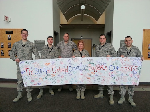 New York Air National Guard Senior Airman Zach Taillie (left) and fellow airmen of the 174th Attack Wing's Command Post section pose with the SUNY Cortland American Red Cross club banner at Hancock Field Air National Guard Base, Syracuse, New York. Senior Airman Taillie was recently selected to serve as Chair of the Armed Forces Committee of the Red Cross chapter. The banner is filled with signatures of students from SUNY Cortland. (Photo by New York Air National Guard Tech. Sgt. Philip Benjamin/Released)